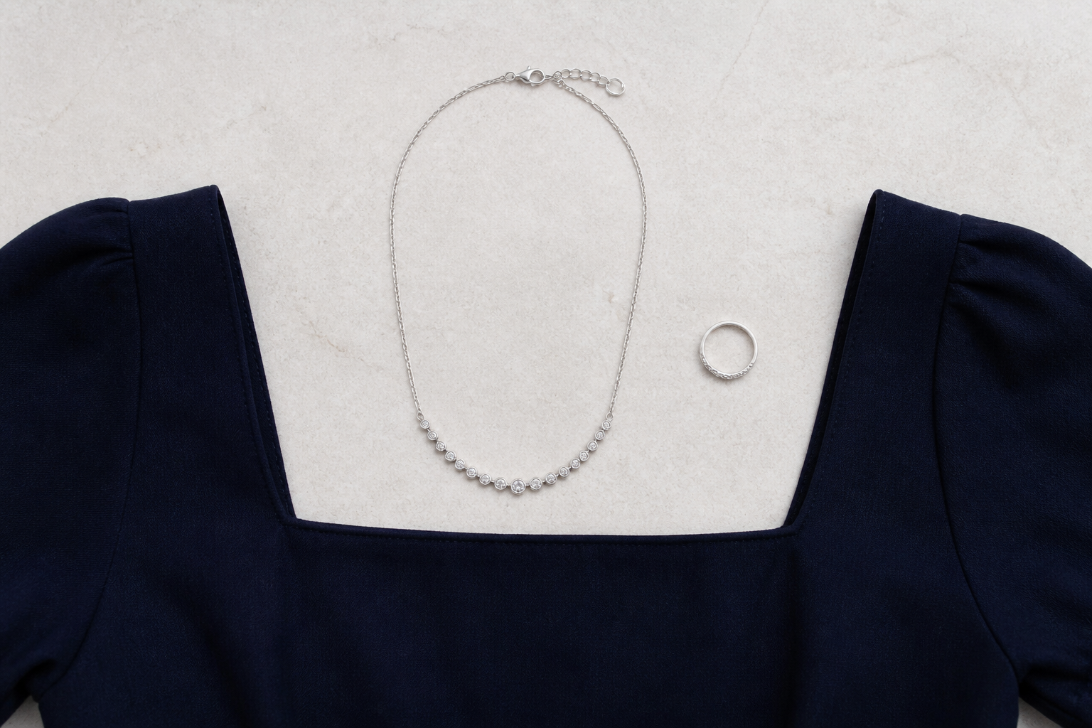 Collar plateado colocado sobre un escote cuadrado azul marino