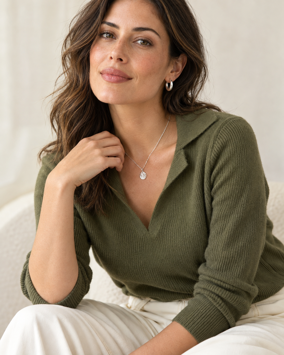 Mujer con suéter verde oliva que combina aros y collar plateados