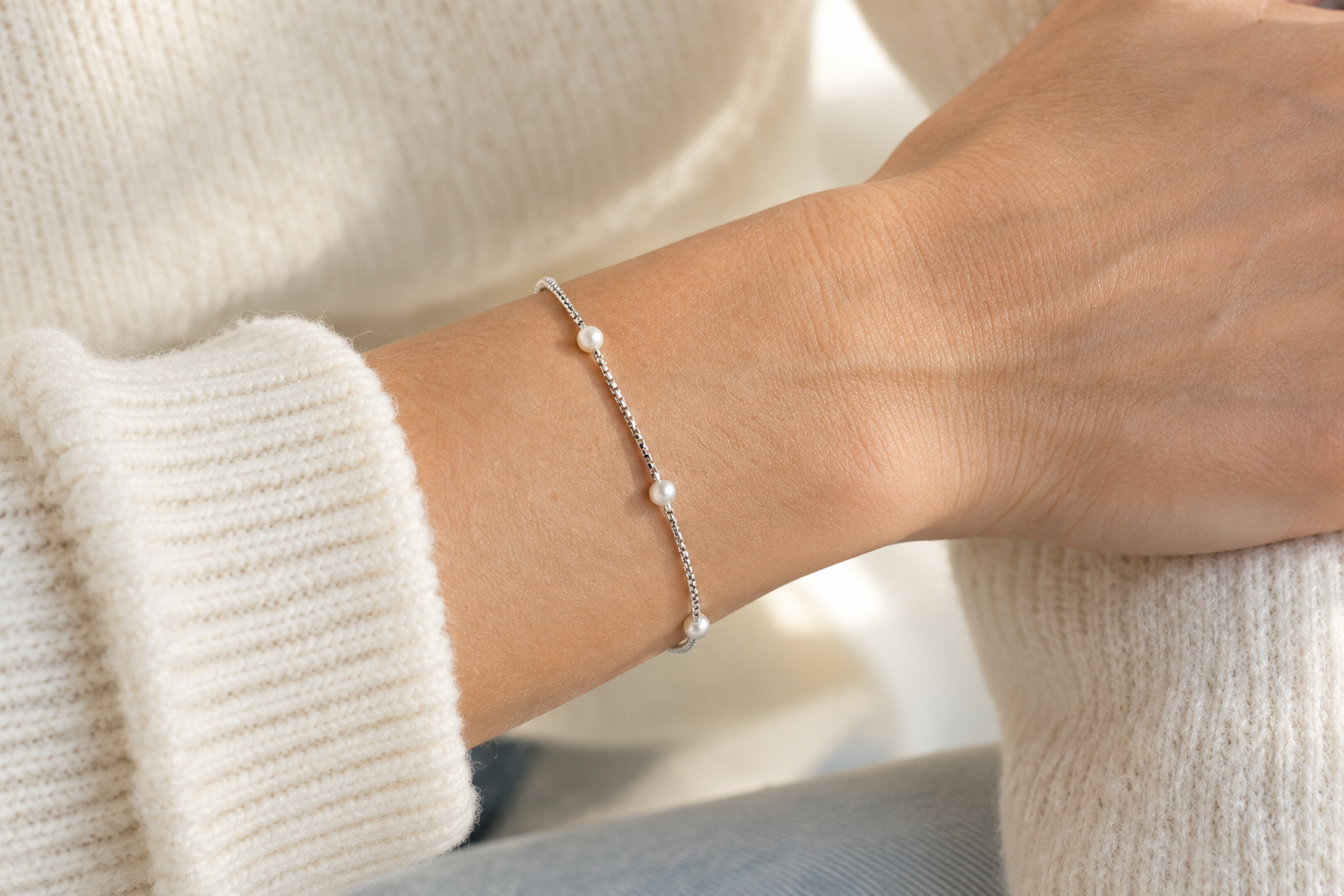 Pulsera veneciana plateada con pequeñas perlas sobre una tela marfil