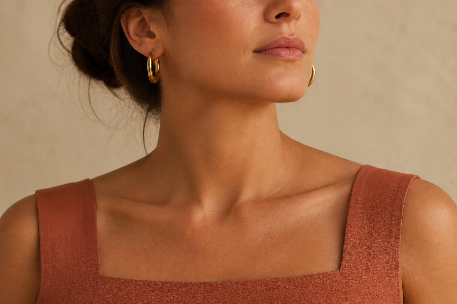 Mujer con escote cuadrado terracota y argollas doradas sin collar