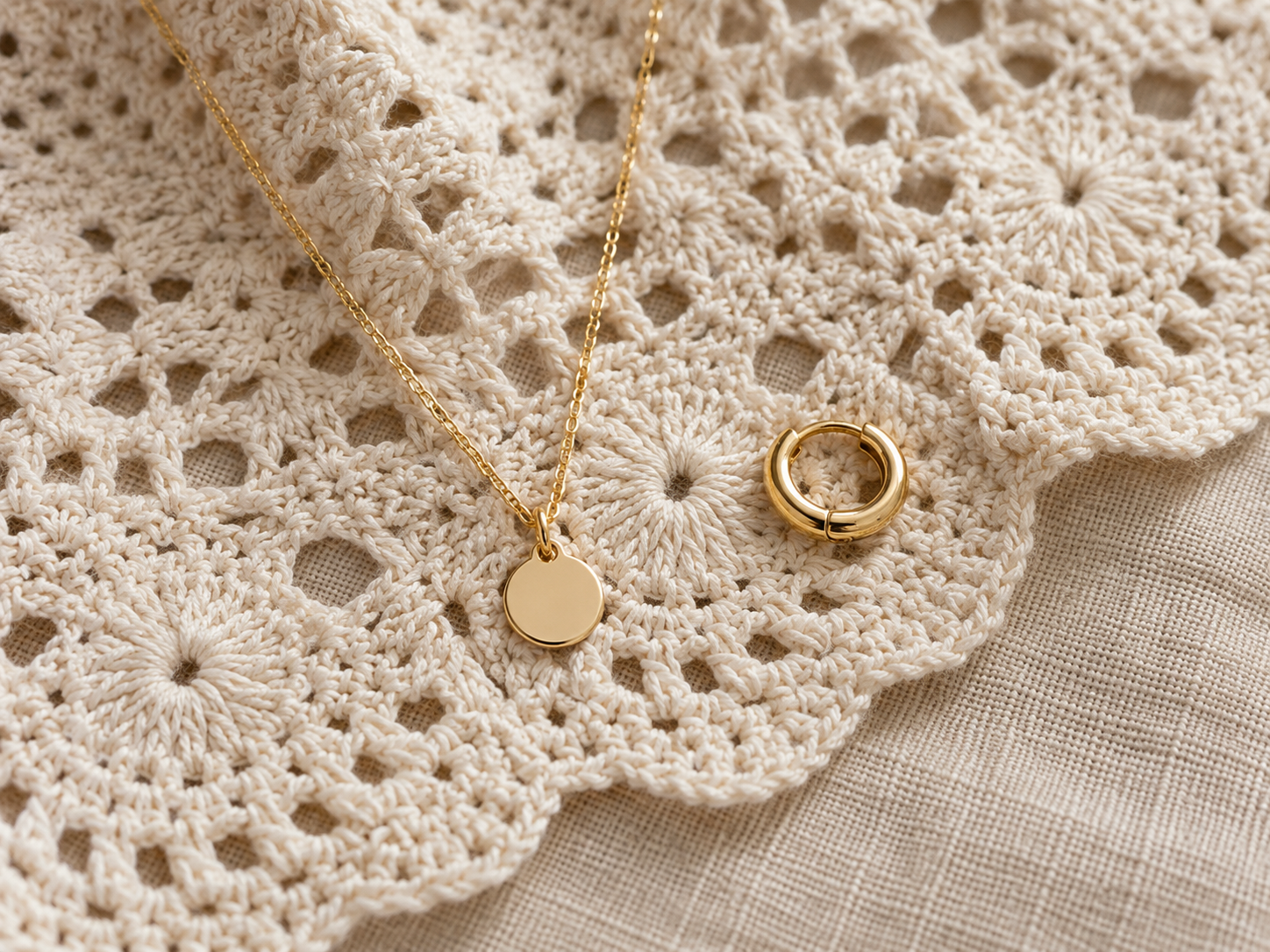 Collar delicado y aros dorados sobre una prenda de crochet claro