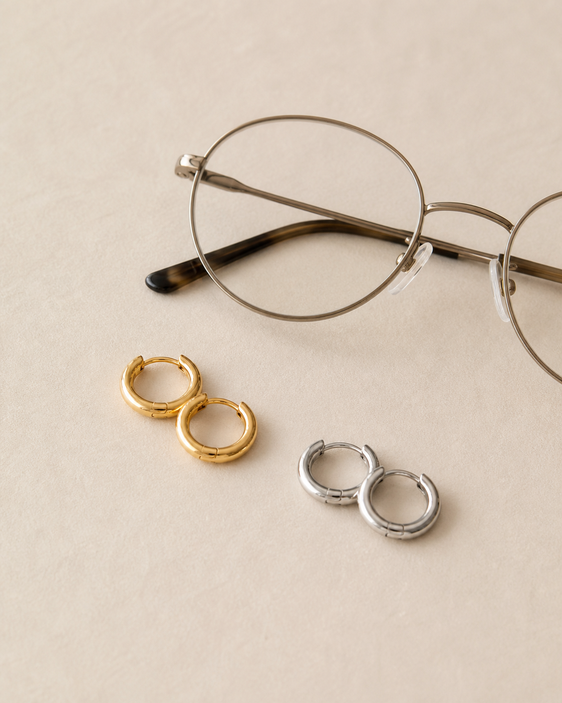 Argollas doradas y plateadas pequeñas junto a lentes de marco metálico