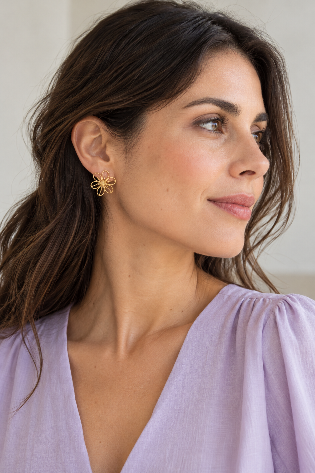 Aro floral dorado en una oreja con blusa lila para un look equilibrado