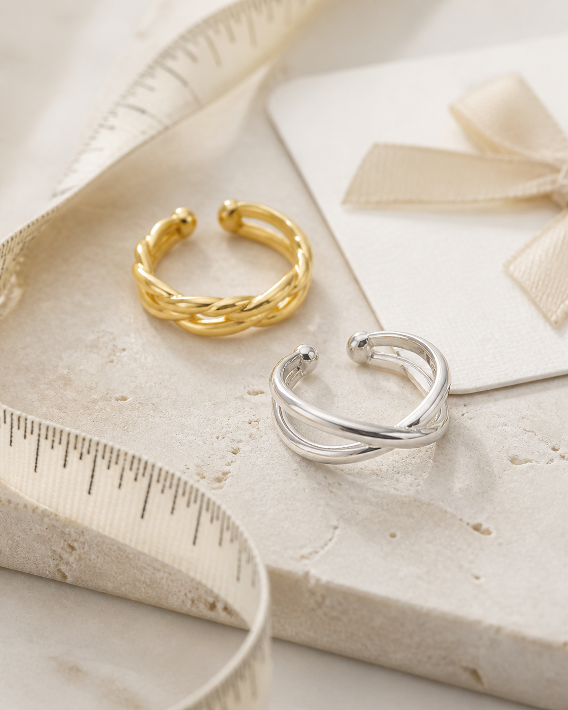Anillos ajustables dorados y plateados junto a una cinta de medición