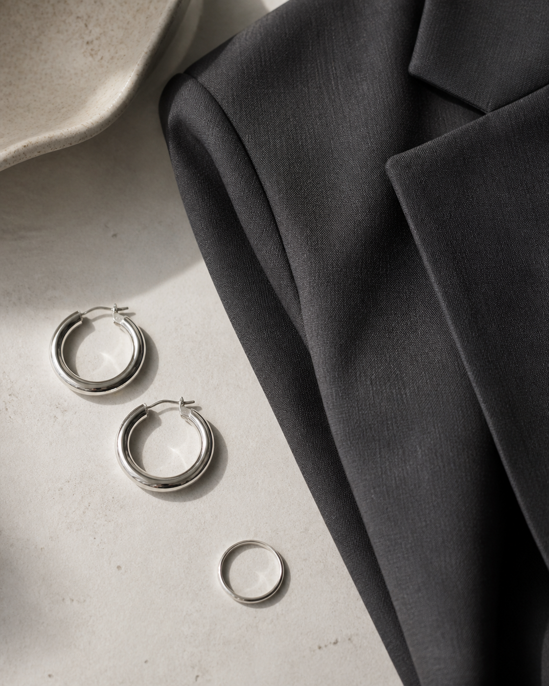 Aros plateados y anillo fino junto a un blazer gris oscuro