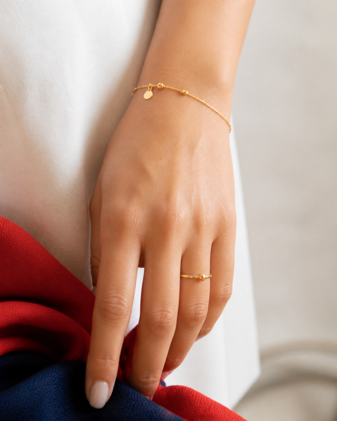 Mano con pulsera fina y anillo bañado en oro para combinar en Fiestas Patrias