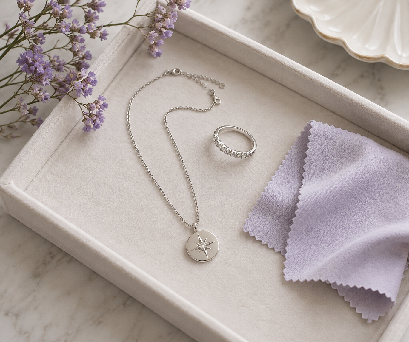 Collar y anillo plateados guardados junto a un paño suave para proteger su acabado