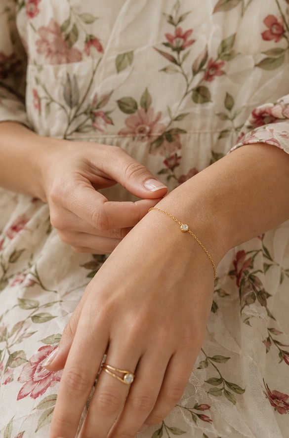 Pulsera fina y anillo dorado combinados con vestido de flores claro