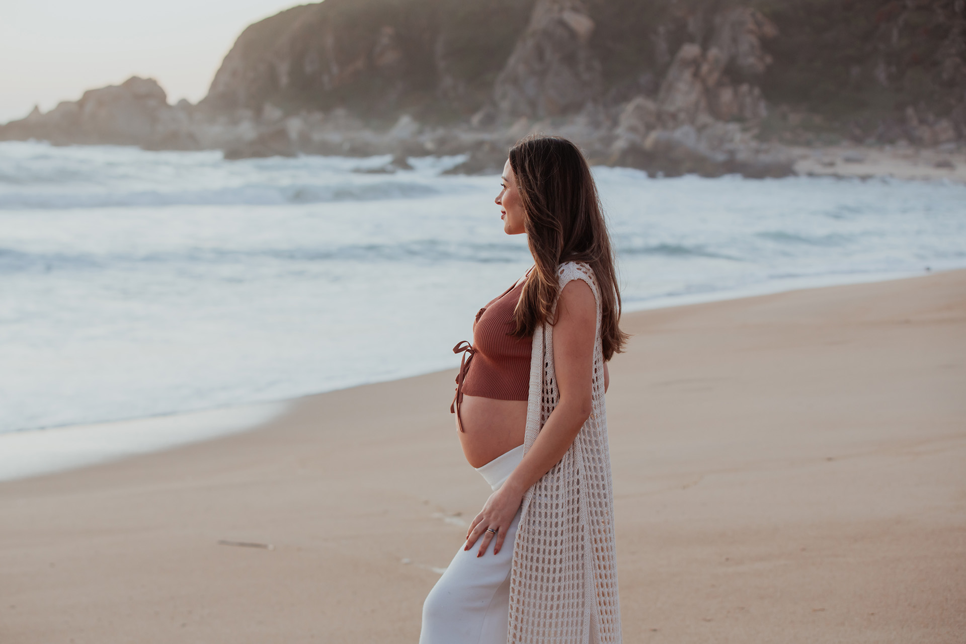Sesión de fotos de embarazo en la playa al atardecer
