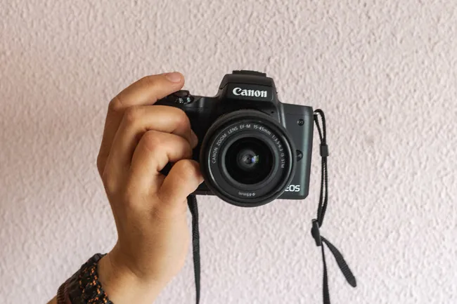 Mano sosteniendo una Canon EOS compacta, imagen ilustrativa para entender qué es una cámara mirrorless.